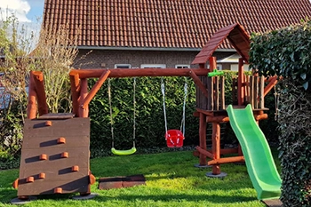 Spielgerüst mit Schaukel, Kletterwand und Rutsche im Garten
