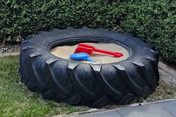 Großer Sandkasten aus Traktorreifen mit Spielzeug für Kinder im Ferienhaus in Hooksiel