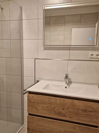 Waschbecken mit Holzunterschrank und Spiegelbeleuchtung