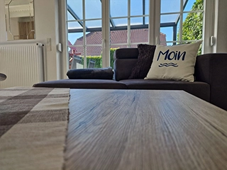 Sofa mit Moin-Kissen vor großer Fensterfront
