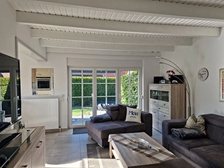 Wohnzimmer mit Fernseher und offener Küche