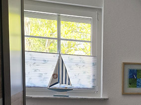 Modern eingerichtetes Kinderzimmer mit Fensterblick und und Insektenschutz